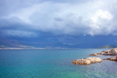 Adanın üzerinde alçak bulutlar. Deniz manzarasında izler var. 