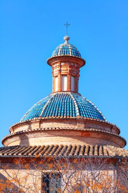 Mavi çatı kiremit kubbesi. Tepesinde haç olan çan kulesi 