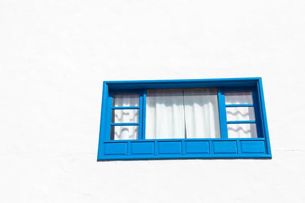 Blue window at white wall . Wooden window with white curtains