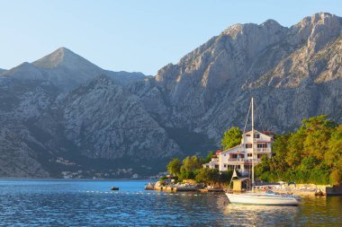 Coastal cottage and moored yacht . Summer vacation resort near mountain and water bay 