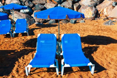Sun loungers and umbrella on the beach . Seaside summer vacation