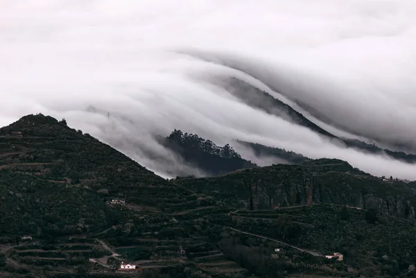 Clouds over rolling hills . Low clouds cover mountains