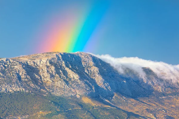 Beautiful rainbow over the mountain . Scenic view of rainbow and clouds over the mountains