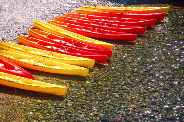 Colorful kayaks on the shore . Water sport boats in a row