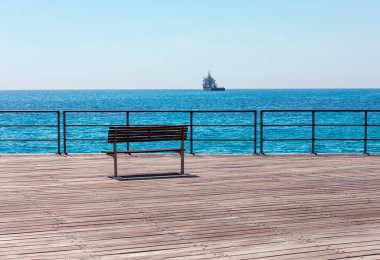 Sahilde kimsesiz bir bankta. Balustrade ve mavi denizle kıyıda