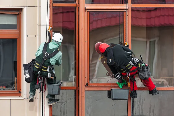 Workers washing windows at exterior building . Rope access window cleaning services