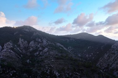 Gün batımında dağ manzarası. Dağların tepesinde bulutlar 