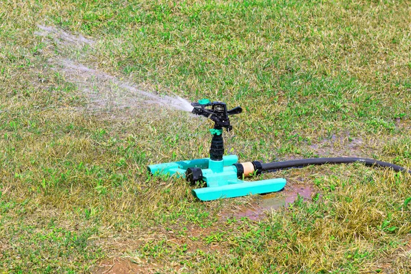 Lawn irrigation with sprinkler . Spraying water on the green grass in the park