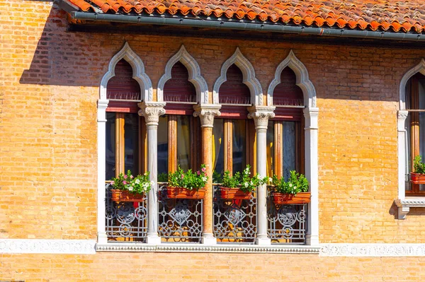 House with windows with arches and columns . Detail of the facade of an old house in Venice, Italy .  Brick wall decorative details within the arches and columns