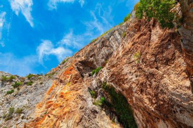 Uçurum mavi gökyüzüne karşı sert ve dokulu yüzeyleri olan doğayı yonttu. Doğal kil kayalık dağ 