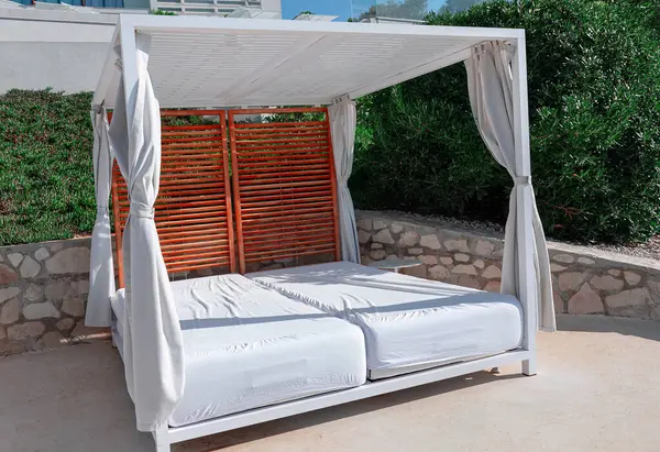 White canopy bed positioned on the terrace of a luxurious coastal resort . White bed contrast beautifully with the natural hues of the coastal environment