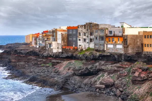 A row of houses is perched along the edge of an ocean landslide coast . Colorful houses on the coast of Gran Canaria, Canary Islands, Spain
