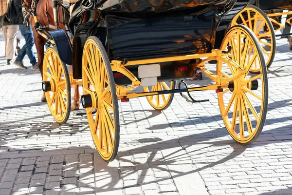 Horse carriage with yellow wheels on the city street . Charming horse carriage draws attention with its classic design and distinctive feature
