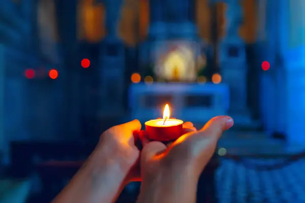 Burning candle in the hands on the background of the church