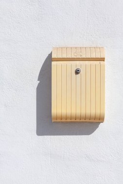 Beyaz bir duvarda, güneşin gölgesi olan bir posta kutusu.