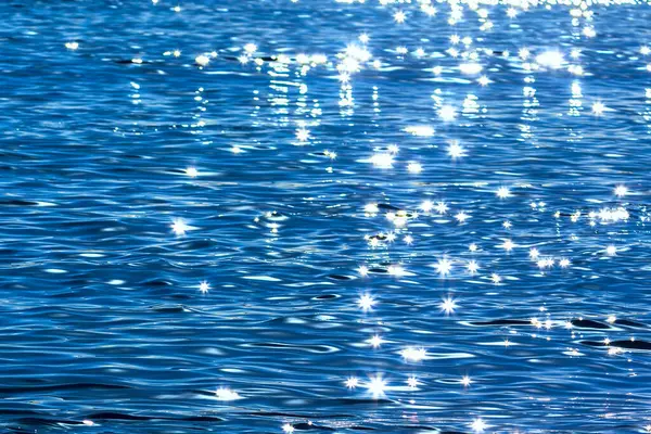 Güneş ışınları ve bokeh ile mavi su yüzeyi, soyut arkaplan