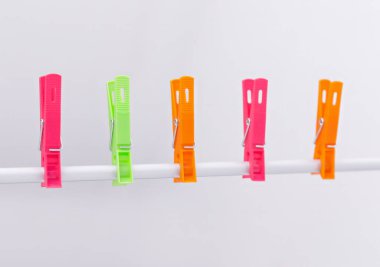 Beyaz arkaplanda izole edilmiş çamaşır ipindeki renkli mandallar