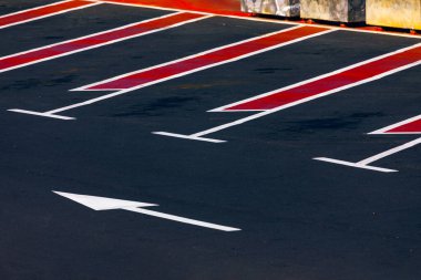 Şehirdeki bir otoparkta kırmızı ve beyaz oklar. Otoparkta yol işareti