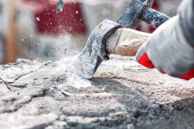 İşçi, betonla taş kesmek için balyoz kullanıyor. İnşaat işçisi