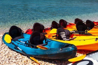 Çakıl taşlı sahilde renkli kanolar. Kürek çeken su sporu tekneleri