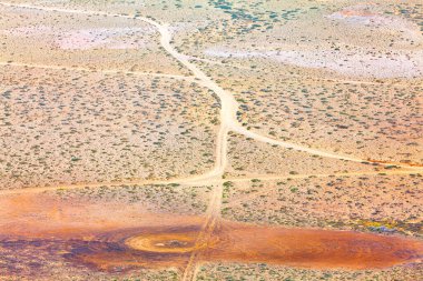 Çorak bir çölün içinden geçen virajlı toprak yol. Namibya, Afrika 'daki Namib Çölü' nün havadan görünüşü