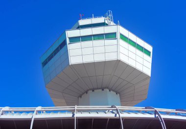 Arka planda mavi gökyüzü olan havaalanı kulesi. Binanın eşsiz bir şekli var ve o bir kule. Havaalanı kontrol kulesi, aşağıdaki pistlerdeki hareketli aktiviteyi denetlemek için dik duruyordu.