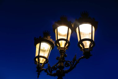 Geceyi aydınlatan üç ışıklı sokak lambası var. Lambalar bir bakıma aynı anda parlıyor, birlik ve ahenk duygusu yaratıyor.