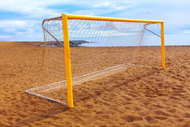  Kumlu sahilde beyaz ağlı bir plaj futbolu kalesi. Sarı kale direği, kumlu sahilde beyaz ağlı.