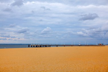 Rıhtımı ve bulutlu gökyüzü olan bir sahil. Arcachon Frangı 'nda Thiers' in kumlu plajı.