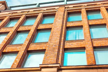 Çok sayıda penceresi olan yüksek bir bina, açık bir günde güneş ışığını yansıtıyor. Modern yüksek katlı bina, bir sürü pencereyle süslenmiş.