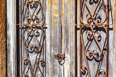 Kapıdaki demir parmaklıklar paslanmış ve eski moda bir görünüme sahip. Ahşap kapının bir sürü detayı var, ızgaralar da dahil. Manzara nostaljik ve ürkütücü.