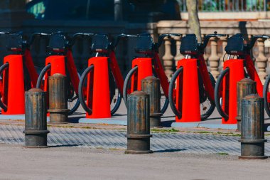 Row of red bike racks are lined up on the sidewalk for rent. Bicycles standing in a straight line clipart