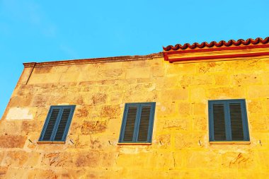 Sarı duvarı, üç penceresi ve mavi süslemesi olan bir bina. İspanyol iskan evi