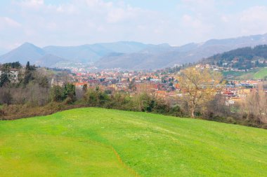 İtalya 'daki Bergamo şehrinin panoramik manzarası. Yerleşim yerleriyle yeşil alan ve arka planda dağlar
