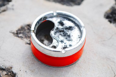 Kırmızı ve gümüş sigara tutacağı yerde duruyor. Tutucu kirli ve içinde bir delik var.