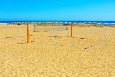 Voleybol ağı kumlu bir plaja kurulmuş. Sahilde voleybol ağı, arkasında okyanus var.