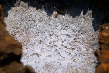 Taze tuz tabakasıyla kaplı kaya yüzeylerin dokusunu ve kontrastını vurguluyor.