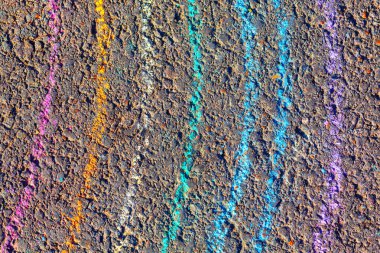 Kaldırıma yayılmış renkli bir gökkuşağı çizimi. Beton bir yüzeye renkli tebeşir çizimi. Renkler parlak ve canlı, eğlenceli ve eğlenceli bir atmosfer yaratıyor.