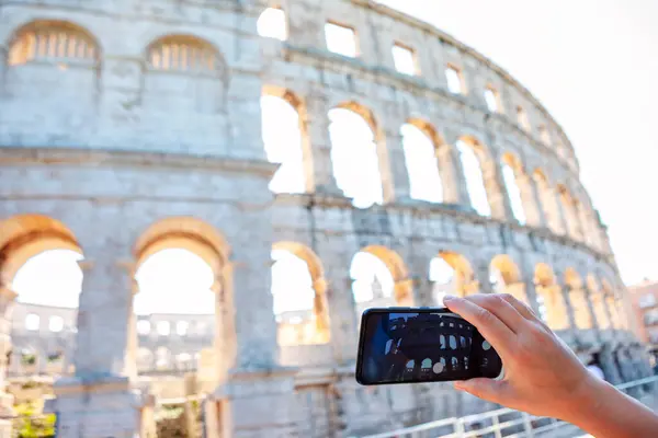 stock image Photographer capturing the beauty of an ancient building. Person is taking a picture of Pula Amphitheatre with a cell phone