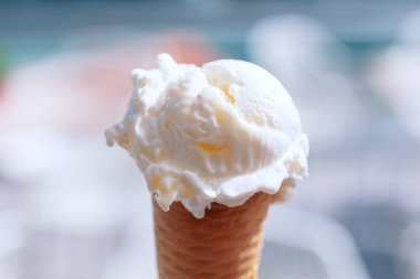 Renkli dondurma külahı, güneşli bir günde tatlı bir ziyafetin tadını çıkarmaya hazır. Üstünde bir top dondurma olan beyaz dondurma külahı. Koni hasırdan yapılmıştır ve kahverengi bir tabanı vardır.