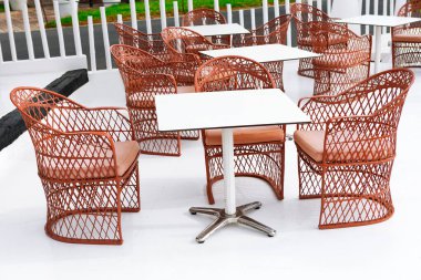 Etrafı sandalyelerle çevrili ahşap masalarla dolu rahat bir teras, açık hava yemek ve rahatlama için mükemmel.