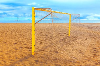 Futbol golü kumlu bir plajda duruyor. Plaj futbolu için sarı kale direği