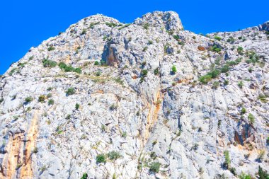 Gri kayalık arazili bir dağ. Dağ zirvesi güzel ve görkemli bir manzaradır. Kayalık arazisi ve ağaçlar manzaraya biraz yeşillik katar.