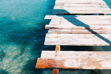 Kırık kalasları olan eski ahşap iskele. Sakin suya bakan ahşap iskele.