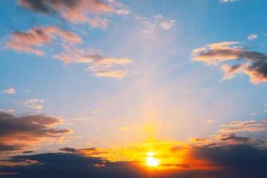 Gökyüzü alacakaranlıkta ılık turuncu bir tonla parlıyor. Sakin günbatımı okyanus üzerinde canlı renkler bırakır, kabarık bulutlar gökyüzünün ılık renklerini yansıtır.