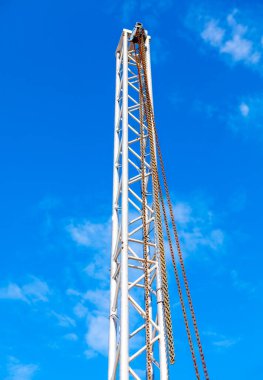 Kaldırmak için zincirleri olan metal kule. Açık mavi gökyüzünün altındaki bir binanın tepesinde.