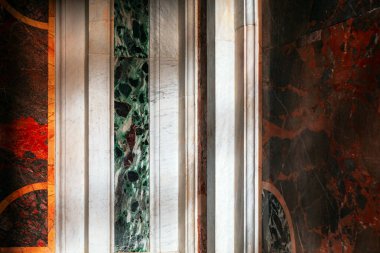 Duvarın çeşitli mermer panellerle süslenmiş kısmı. Paneller, dikey şeritler halinde dizilmiş yeşil, beyaz, kırmızı ve siyah renkler de dahil olmak üzere farklı renk ve desenleri sergiler.