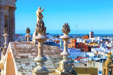 İspanya, Endülüs 'teki Cadiz Katedrali' nin tepesindeki İsa heykeli. Heykel çatıda, alevlere benzeyen süslü taş yapılarla çevrili. Sayısız binayla panoramik şehir manzarası