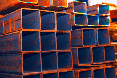 Paslı yüzeyi olan dikdörtgen, içi boş çelik borular. Endüstriyel sahne, oksitlenmenin metal üzerindeki etkilerini vurgular ve bu malzemelerin inşaat veya imalatta potansiyel kullanımını önerir