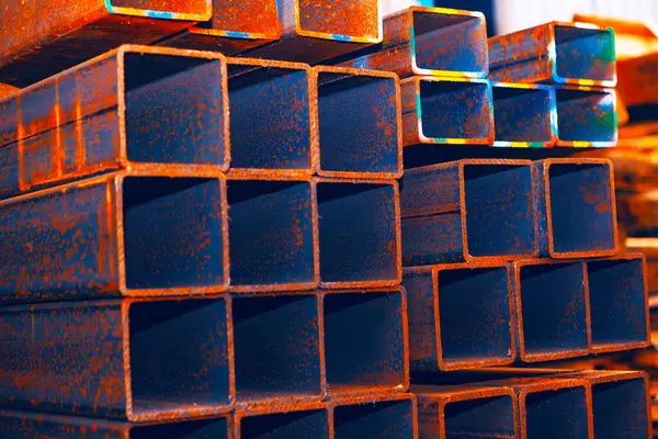 Paslı yüzeyi olan dikdörtgen, içi boş çelik borular. Endüstriyel sahne, oksitlenmenin metal üzerindeki etkilerini vurgular ve bu malzemelerin inşaat veya imalatta potansiyel kullanımını önerir